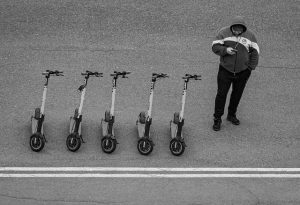 A man with a hoodie prepares to ride his best scooter. 