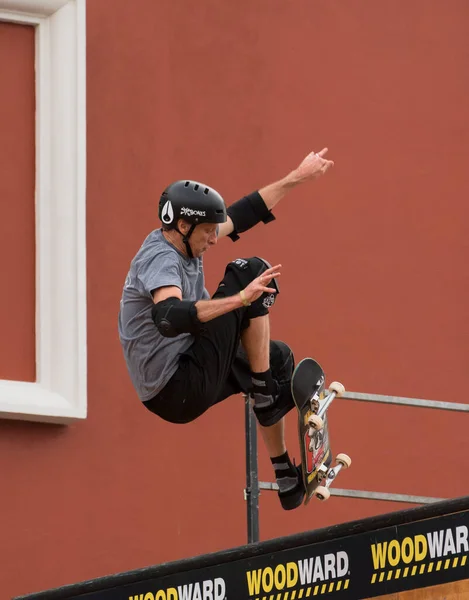 A man with a black helmet practices his skateboard tricks confidently while wearing his skateboard protective gears. 