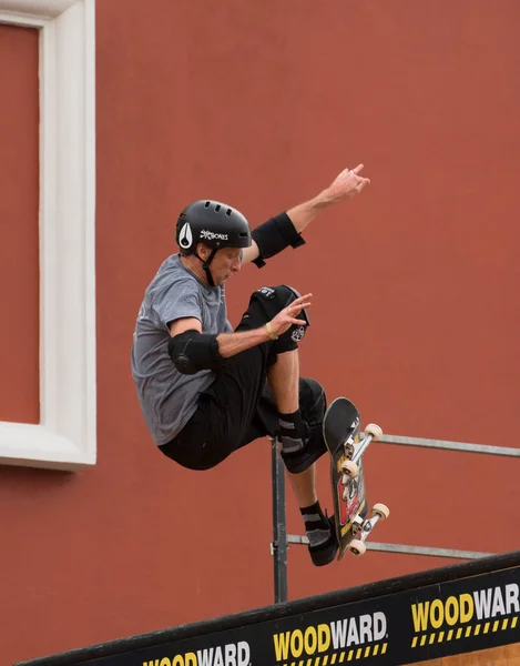 SkatingTrick: A man with a black helmet practices his skateboard tricks confidently while wearing his skateboard protective gears.