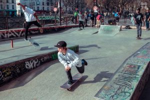 Boy wearing a white sweatshirt and black hat, skillfully skating on a smooth surface. Best Skateboards to consider. 