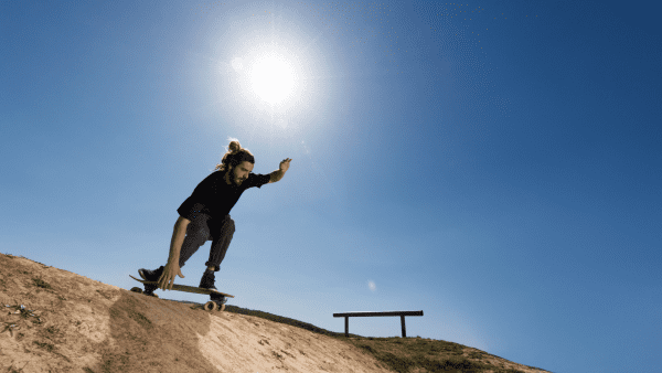 A man with a black shirt & comfy pants, balancing while going down with his board.