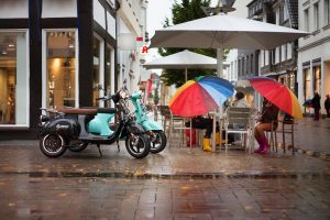  Two scooters are parked outside the building while it’s raining