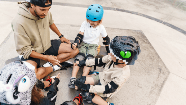 A man and some children wearing skateboard protective gear