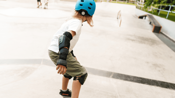 A kid wearing his gear while balancing on his board at the skate park