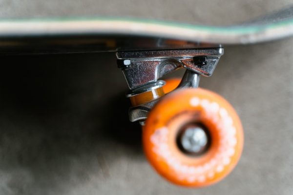 Orange wheels attach on skateboard truck ready to be used at the parks