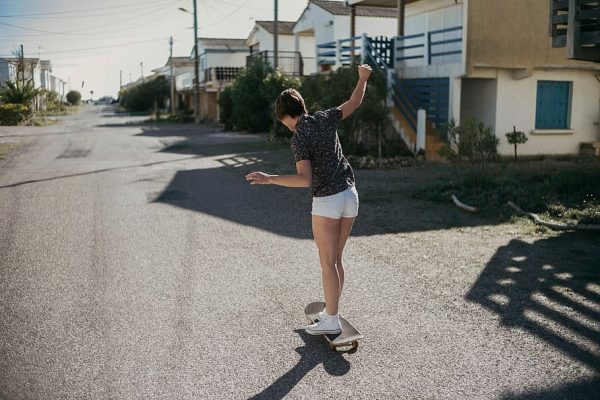 A female rider is enjoying women's skateboard clothing line. Common options of women's clothing for this sport are shorts, t-shirts, socks and sneakers. Bold graphics, baggy pants, and oversized t-shirts became staples of both men's and women's board riding fashion scene. 