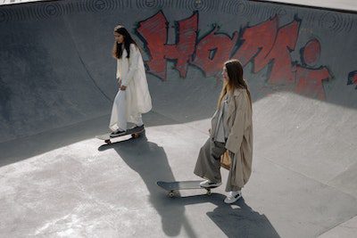 two women skateboarding together in the skate park in style