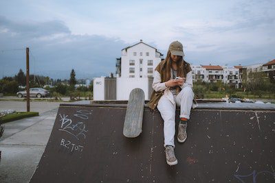 a woman with her skateboard next to her, texting