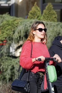 Electric scooter: A woman riding in an electric scooter a red shirt and black pants rides her scooter while enjoying the view of the park.