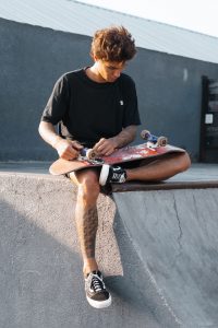 Young lad maintaining a skateboard.