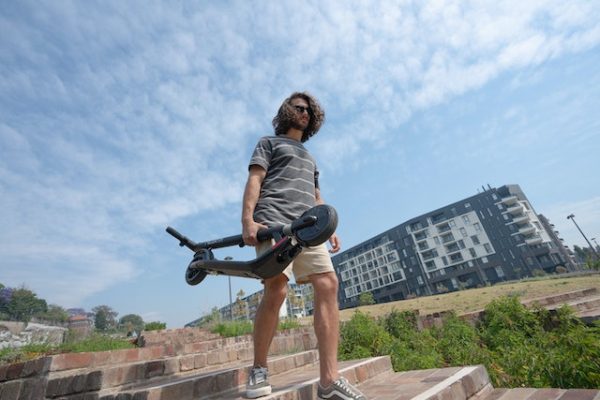 A man carrying his scooter