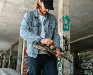 A man with a black cap is cleaning his skateboards.