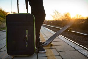 A suitcase and skateboard ready for travel.