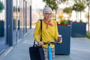 The woman is riding her two-wheeled while carrying a cup of coffee