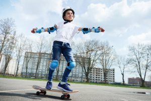 A person is riding a skateboard. His skateboard is just perfect for him as a beginner skater. 