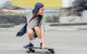 A girl holding and balancing on a skateboard. 