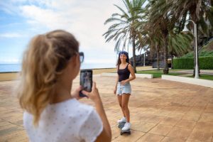The woman rides her skateboard while her friend takes a picture of her. 