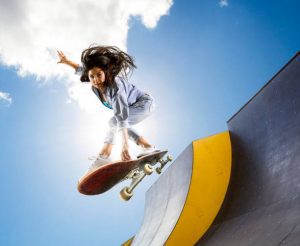 A woman does stunts fearlessly using her board. 