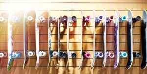 A vibrant display of longboards mounted on a wall, each skateboard featuring a unique design and colorful wheels, highlighting the diverse array of skateboard available for teenagers and enthusiasts in the skateboarding community.