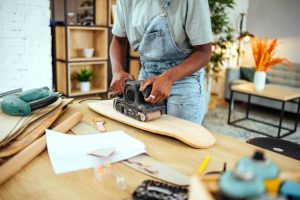 A person makes a handmade board in a brightly-lit room. 