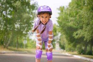 A kid wearing helmet, elbow pads, and knee pads as accessories for longboarding. 