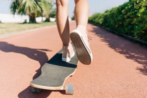 Skateboarder kicking her board in the street with determination.