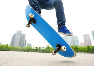 A person who's wearing a blue shoes is doing a trick with a blue skateboard. 