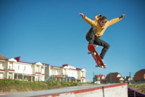 Person wearing yellow shirt shows stunts outdoors using a board. 