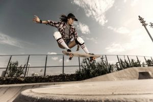 A woman wearing checkered shirt confidently shows her stunts using her board. 