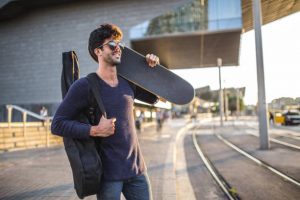 A skateboarder is ready for a travel with his own skateboard. He has the need things.