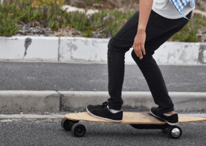 A person wearing black pants rides his skateboard.