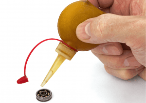 A skateboarder carefully lubricating his skateboard bearing. 