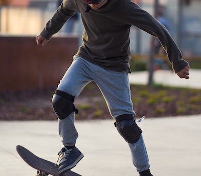 A skateboarder wearing knee pads performing a trick on a skateboard.