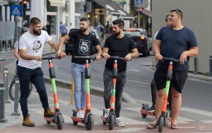 Four men talking to each other while enjoying their best long range electric scooters. 