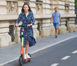 A girl is scooting on the street. 
