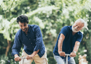 Two adult male are having fun riding kid-sized scooters. They are laughing at their antics.