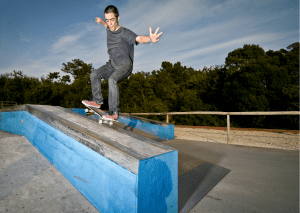 A rider doing slide tricks on the rails. He is wearing demin pants and gray shirt. 