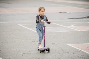 A kid is scooting in the field. 