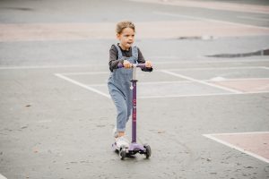 A kid is scooting in the field.