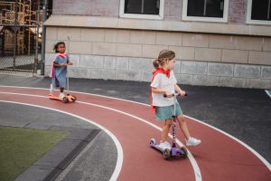 There are two children wearing their best outfit and scooting. 