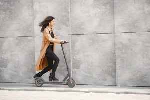 A joyful woman, dressed in casual attire, riding the best scooter of her choice, wearing a radiant smile, relishes her best day as she takes delight in a blissful scooter ride through the picturesque city streets, savoring every moment of the experience.