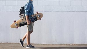 A man holding his chosen skateboard out of the many skateboards from the shop