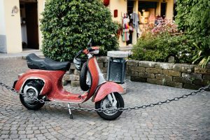 There is a red scooter parking on the side.