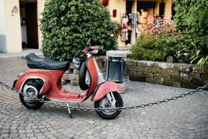 There is a red scooter parking on the side. 