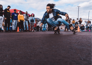 A man doing tricks on roller blades events. The qualities could encounter when riding through an urban setting are replicated in street courses. 