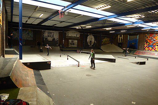 A skater practicing tricks in skate park indoors. 