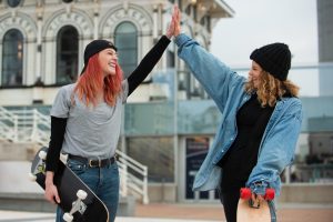 Skateboarders doing a high-five while holding their skateboards.