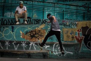 Skateboarders wearing fashionable attire while riding their boards. 