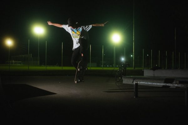 Skateboarder performing tricks in a dark park