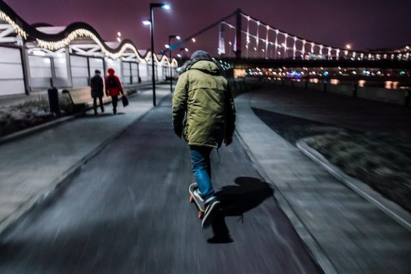 A man with green jacket rides his board at nighttime. 